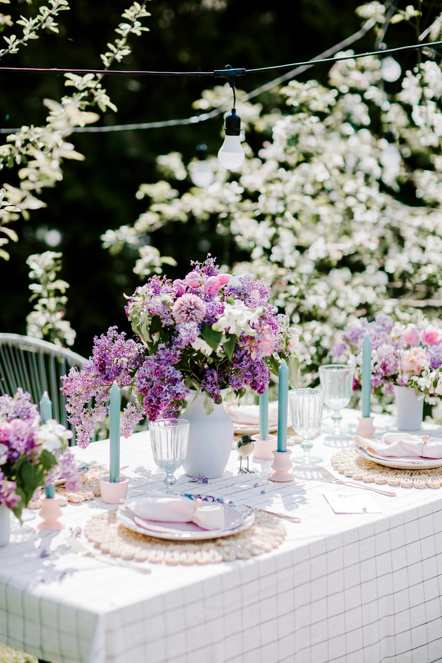 Sommerliche Festtafel mit üppigen Blüten, Kerzen und feinem Gedeck