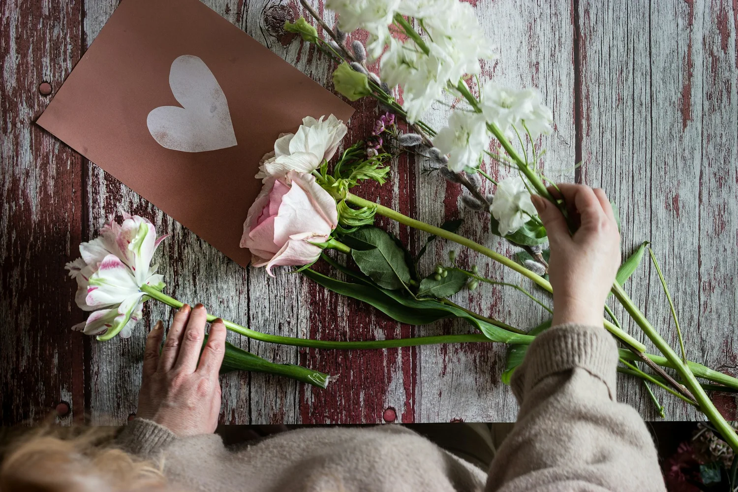 Hände beim Zusammenstellen eines zarten floralen Arrangements